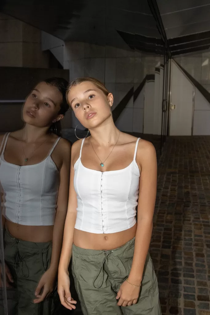 Photo of a blonde teen model wearing a white top and khaki pants
