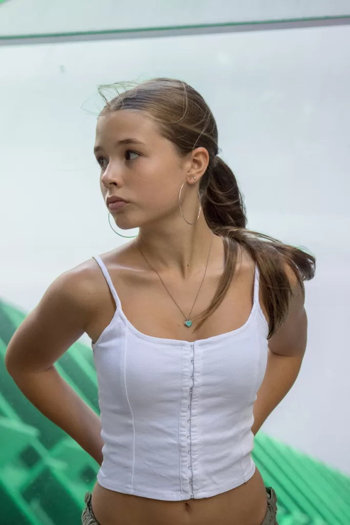 Photo of a blonde teen model wearing a white top and khaki pants