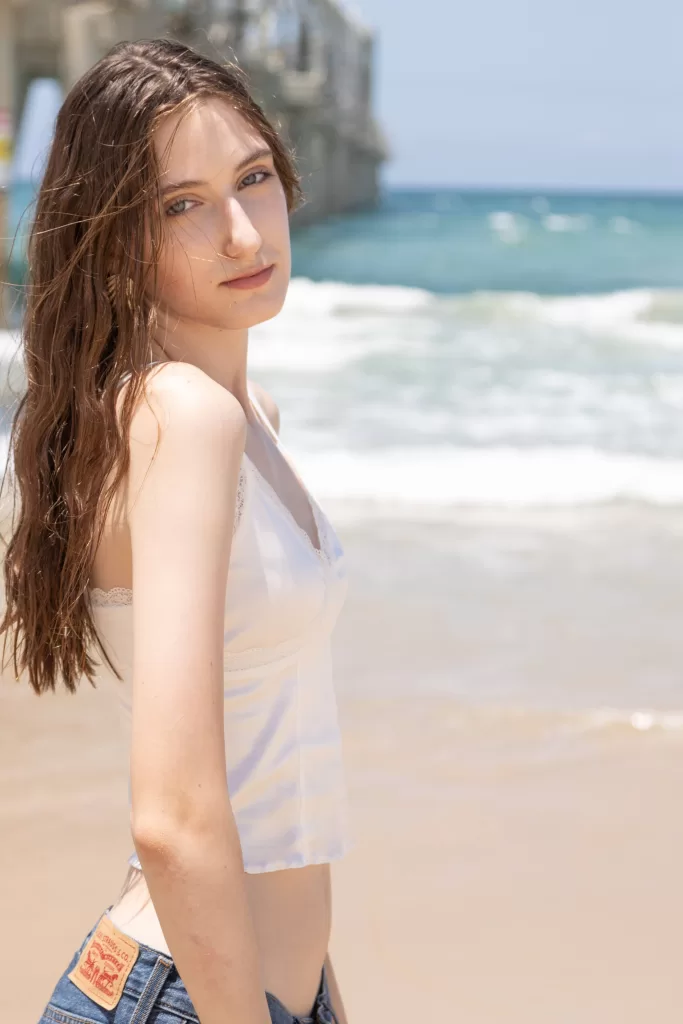Stunning image of a teenage model wearing silky top and standing in an outdoor seaside location