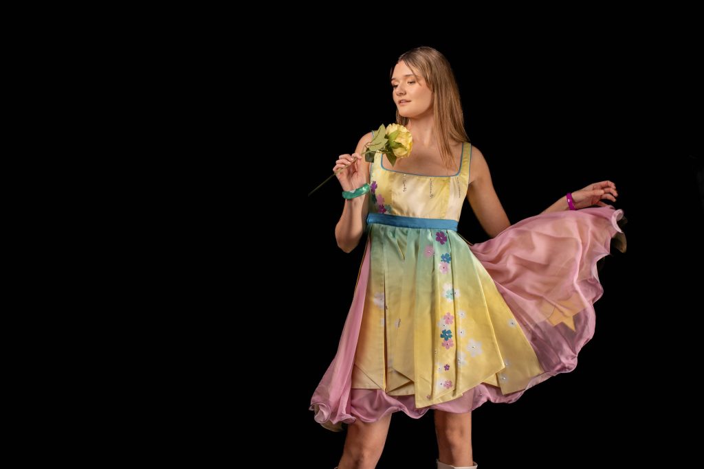 PIcture of a model wearing a colourful dress and holding a flower