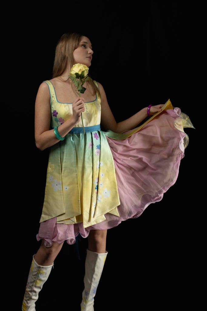 PIcture of a model wearing a colourful dress and holding a flower